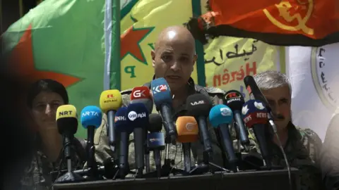 AFP Talal Silo (C) spokesman for the Syrian Democratic Forces (SDF), speaks to reporters in the village of Hazima, Syria (6 June 2017)