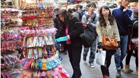 Getty Images People walk through a shopping district in Seoul