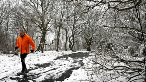 AFP via Getty Images A runner braves the snow on Bidston Hill, near Birkenhead, in north west England on March 9, 2023