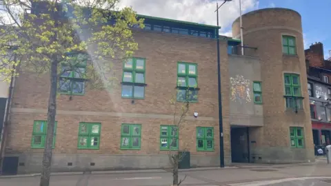 Brian Farmer/BBC Luton Crown Court; A brown-brick build with green-framed windows. The words "CROWN COURT" are written above the entrance