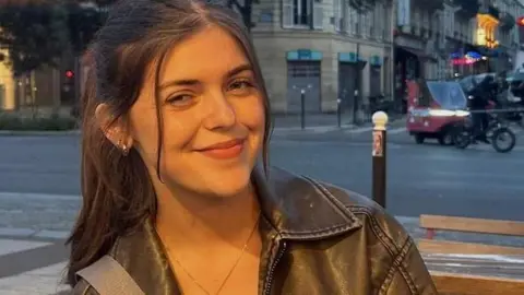 Nel Jones Nel smiling in a leather jacket on a busy city street