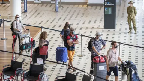 Getty Images Australian passengers from an evacuation flight walk through an airport in Australia