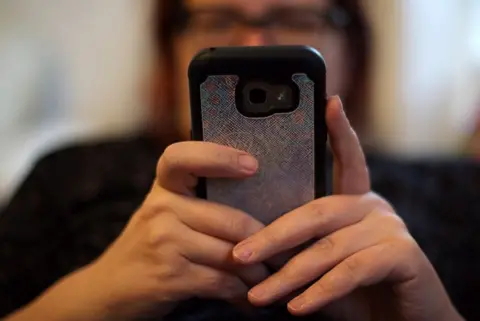 PA Media Woman using her mobile phone