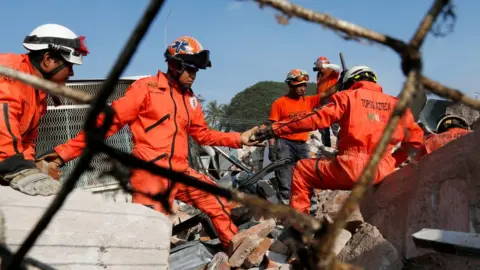 Reuters men in jumpsuits passing rubble along a human chain