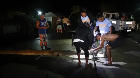 EPA Filipino policemen and villagers clear a toppled post as Super Typhoon Mangkhut approaches the town of Aparri