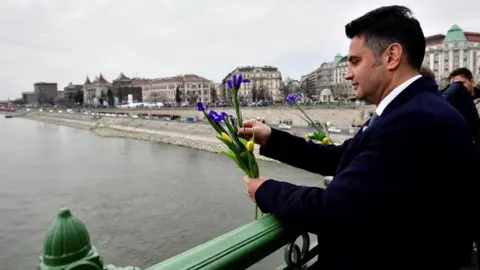 Reuters Opposition candidate for prime minister Peter Marki-Zay throws flowers into Danube River to commemorate Ukrainian people fighting against Russia's invasion