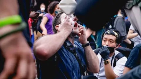 Laura Fuchs Protesters use milk to treat the sting of tear gas in New York City