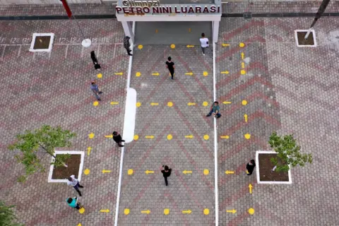 AFP High school students in Albania follow the directions on the ground to enter their building whilst maintaining social distancing