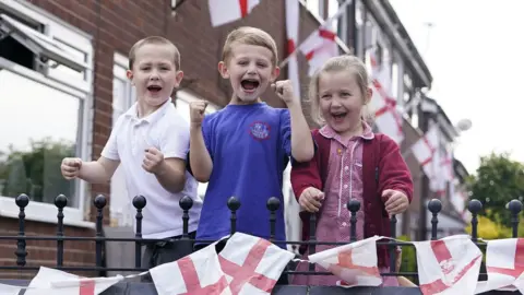 PA Media Young residents on Wales Street cheer for England