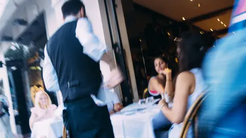 Getty Images A waiter serves diners