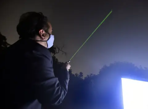 Sonu Mehta/Hindustan Times via Getty Images A man uses a laser pointer