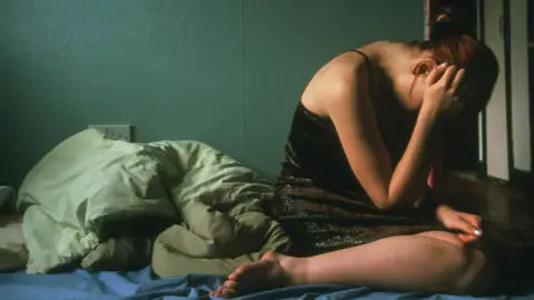 Science Photo Library Depressed adolescent girl holds her head in her hands