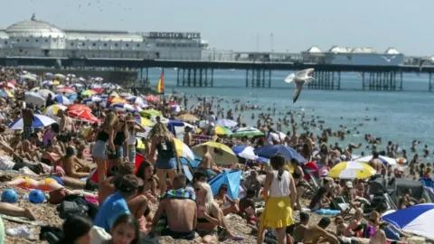 PA Media  People at Brighton beach in August