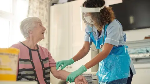 Getty Images Carer helping a care home resident get dressed