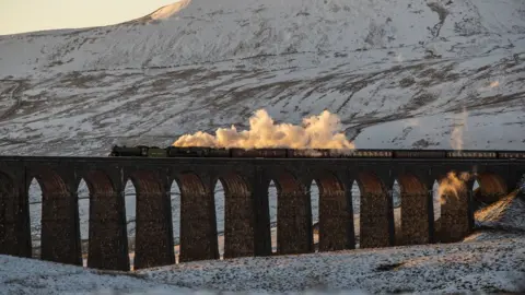 PA A train crosses the Ribblehead Viaduct amid wintry scenes in North Yorkshire.
