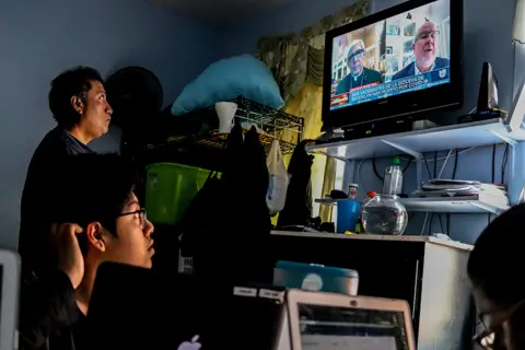  Ana Carmona Ana's father watches news with her brother