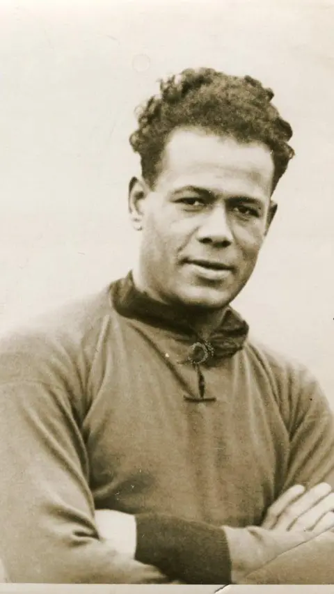 Leslie family Portrait of Jack Leslie. He has his arms folded and is looking at the camera with a smile.