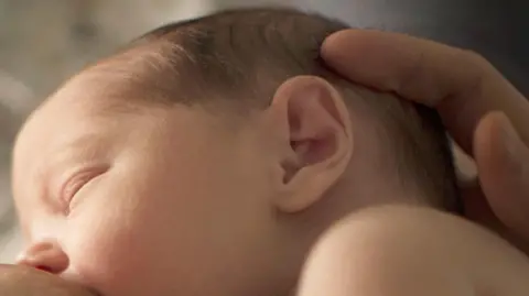 PA A baby with its eyes closed is seen breastfeeding 