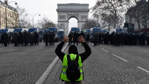 AFP A protester kneels in front of police officers in Paris