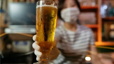 Getty Images A woman in a mask with a glass of beer