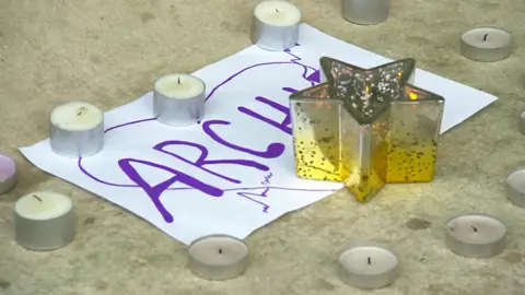 Candles and piece of paper with Archie written on it left at base of Princess Alexandra statue outside Royal London Hospital following death of Archie Battersbee