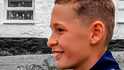 Chris Watkiss A boy with short brown hair looking to the left of the shot and smiling