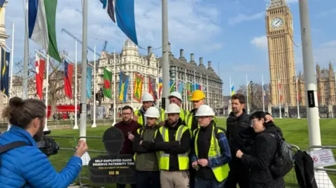 Andrew Sinclair/BBC Campaigner standing outside Parliament to campaign for changes to parental leave