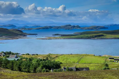 Getty Images Landscape near Achiltibuie. There is a cluster of houses and the sea with the islands of the Summer Isles, and in the distance are hills and mountains.