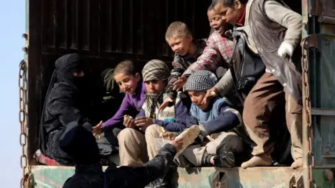 Reuters A fighter from the Syrian Democratic Forces (SDF) gives bread to children near the village of Baghouz, Deir Al Zor province, Syria on 20 February 2019.