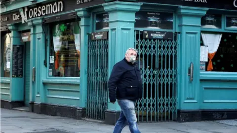 Reuters A man wearing a protective face mask passes Dublin's Norseman pub