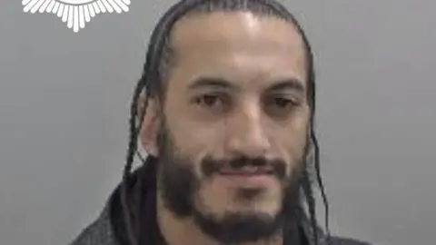 West Mercia Police O'Sullivan also pictured in his police mugshot. He has long dreadlocks and a black beard.
