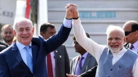 Prime Minister Narendra Modi wearing a white kurta and a blue checked jacket welcomes Israeli Prime Minister Benjamin Netanyahu who is wearing a navy suit, white shirt and a powder blue tie on his arrival at the Air Force Palam airport Station on January 14, 2018 in New Delhi, India.