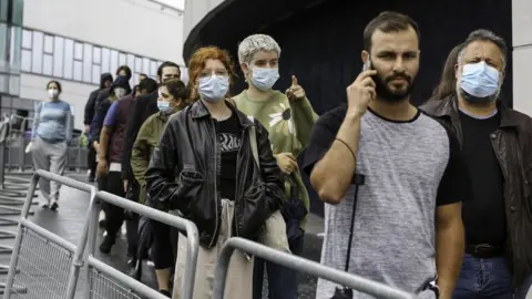 Getty Images People queuing outside a vaccination centre