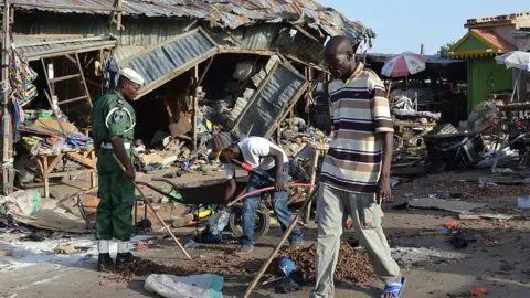 AFP A man walks past a the scene of a bombing after at least 20 people were killed when a young female suicide bomber detonated her explosives at a bus station in Maiduguri, northeast Nigeria, on June 22, 2015 in an attack likely to be blamed on Boko Haram.