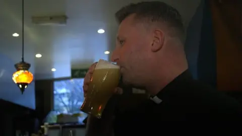 A minister drinking beer at the pub