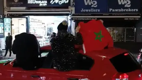 @HarryW34/Twitter Man waves Moroccan flag out of a car window while it drives down Edgware Road