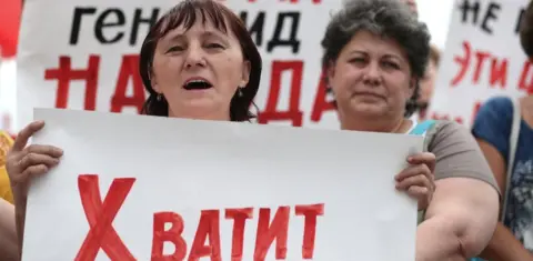 Getty Images A Russian protester in Ivanov on 1 July holds a banner saying "enough"