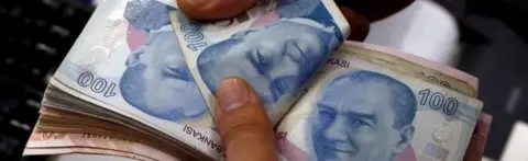 Reuters A man counts Turkish lira banknotes