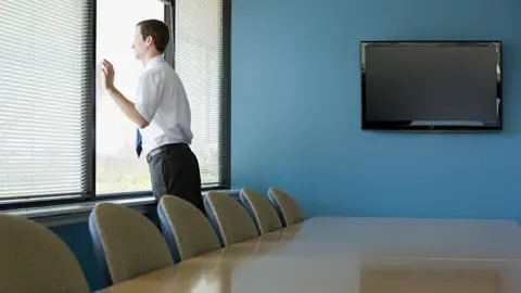 Getty Images Office worker looking through window