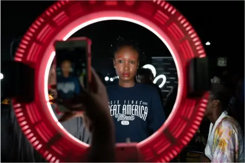 Getty Images A model with red eyebrows posing for a photo in a red ring light.