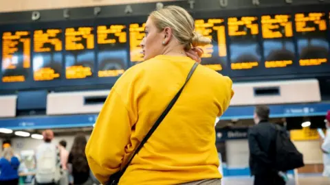 Getty Images Woman looks at rail timetable