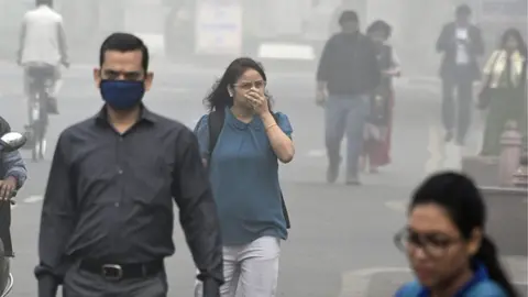 Getty Images Indian people walk on a street as heavy smogs covers New Delhi on November 8, 2017