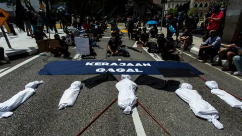 Getty Images Citizens in Malaysia protested in front of fake corpses to symbolise high number of deaths