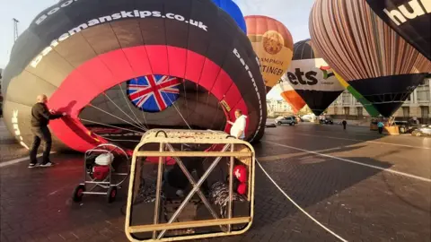 BBC Flight staff inflating a black and red hot air balloon