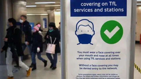 A sign to encourage mask wearing is displayed at a station in London
