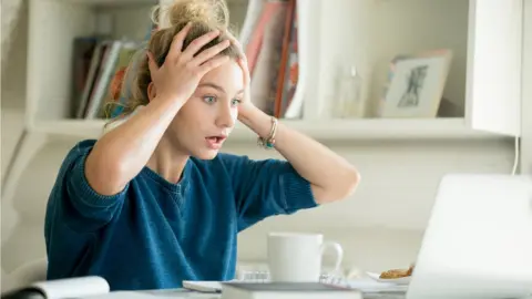 Getty Images Woman holds head in shock