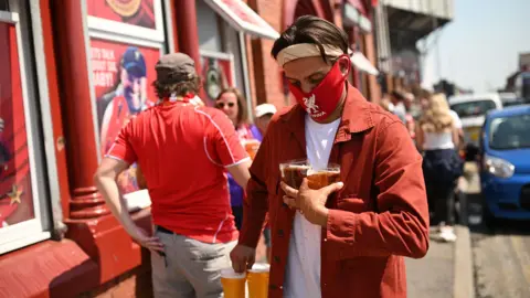 AFP Fan carries beers outside Anfield pub