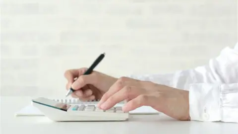 takasuu Woman using calculator in living room