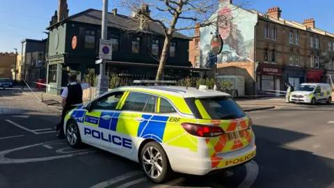 BBC Images showing police car and cordon outside The Duke pub.