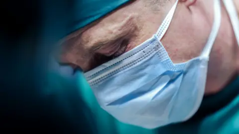 A stock image of a surgeon, wearing a mask